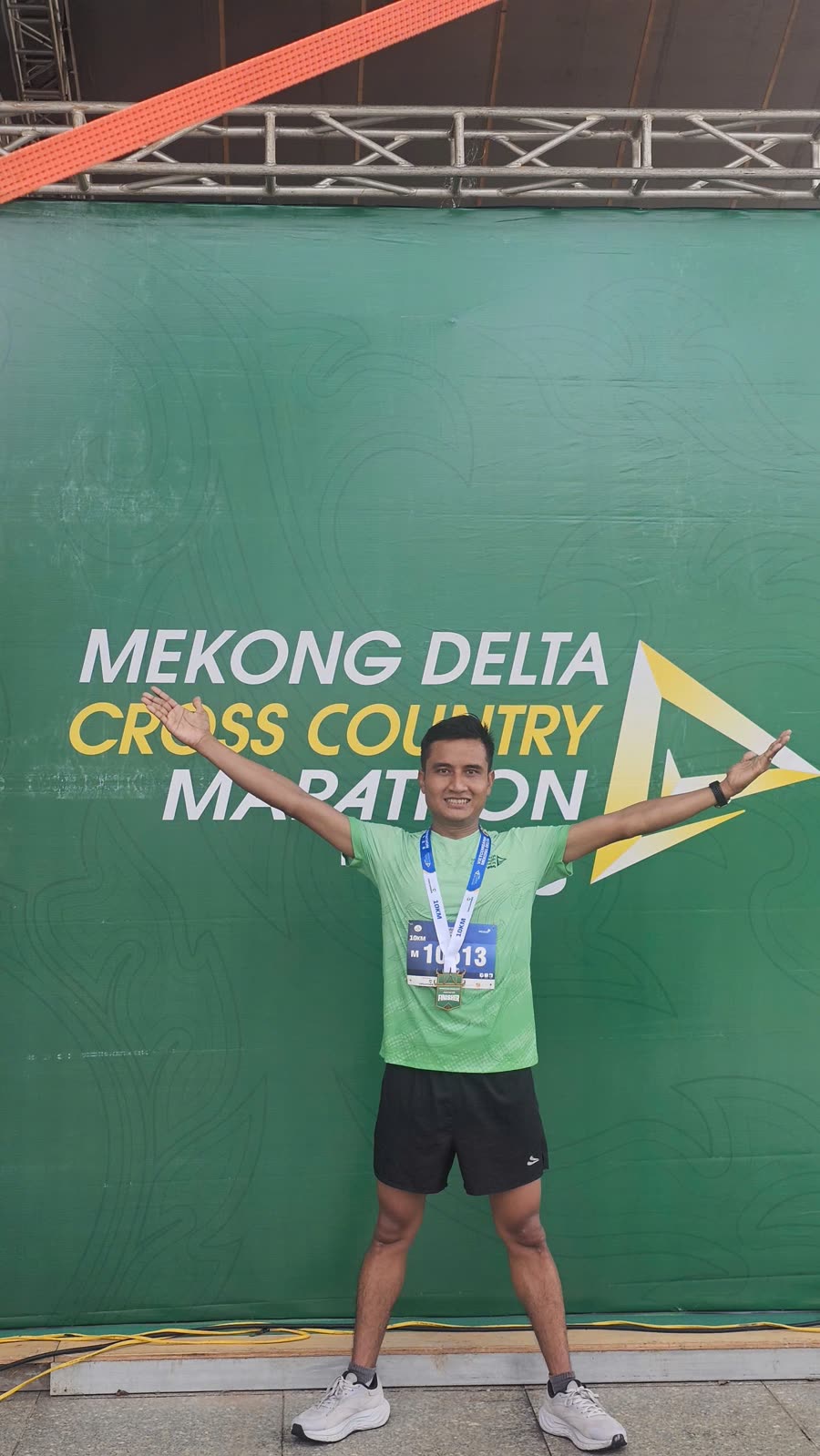Minh dang rộng hai tay trước phông giải Mekong Delta Cross Country Marathon